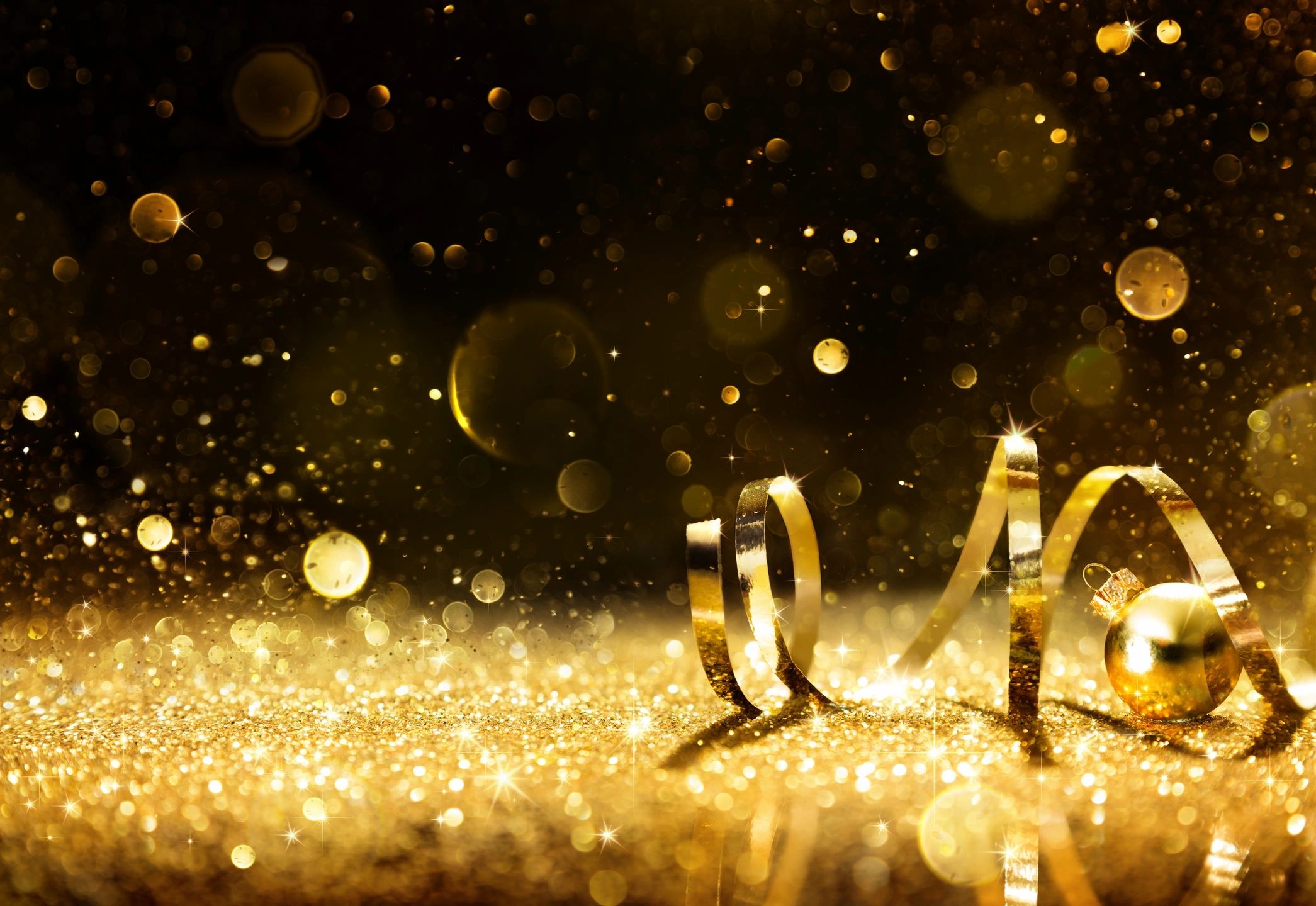 to celebrate the new year, gold confetti and streamers in air against a black background