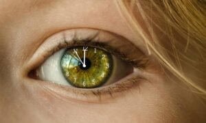 green eye with clock on eyeball showing 11:55