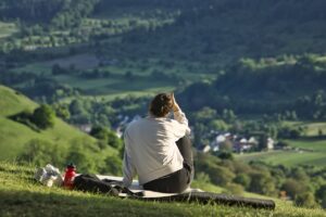 woman sitting on mountain side looking out over valley, resting