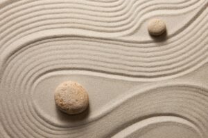 two stones in sand with curves in sand around them