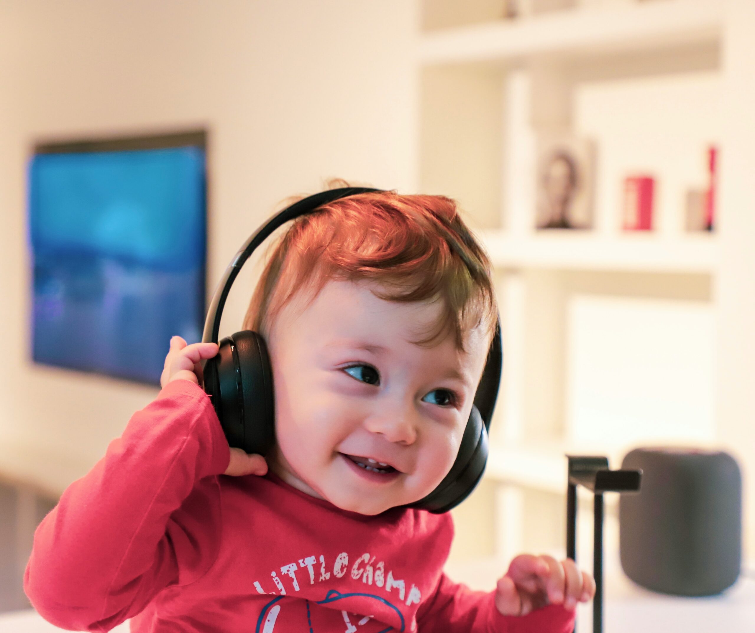 Toddler with headphones smiling at camera.