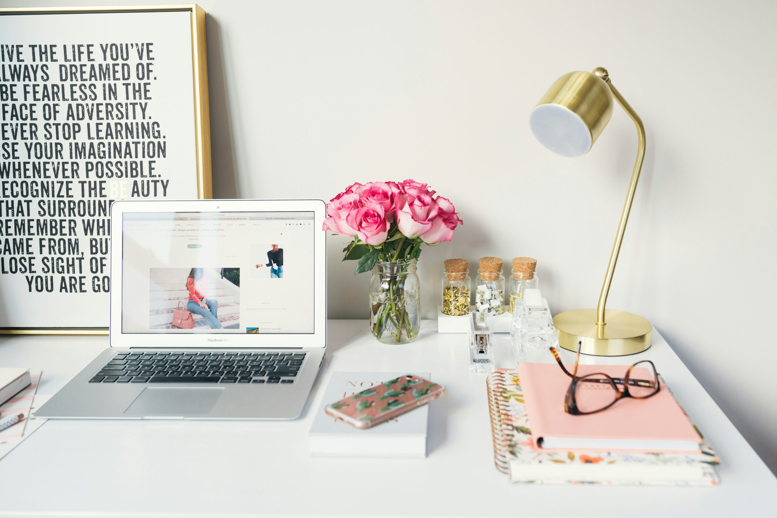 desk owner is trying to get things done, pink notebook, pink flowers on white desk,