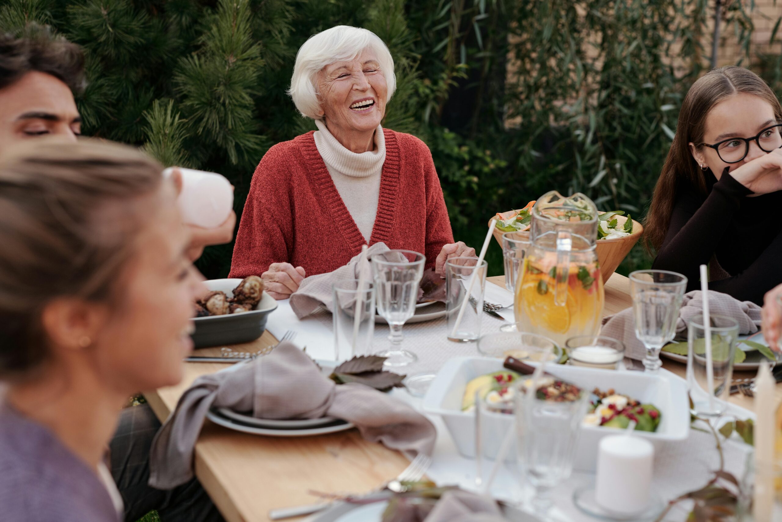 woman with grey hair at head of dinner table with family