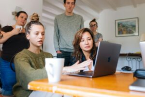 family members gather around laptop for meeting to discuss helping parent downsize