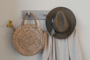 hat, coat and straw bag hanging on wall hooks